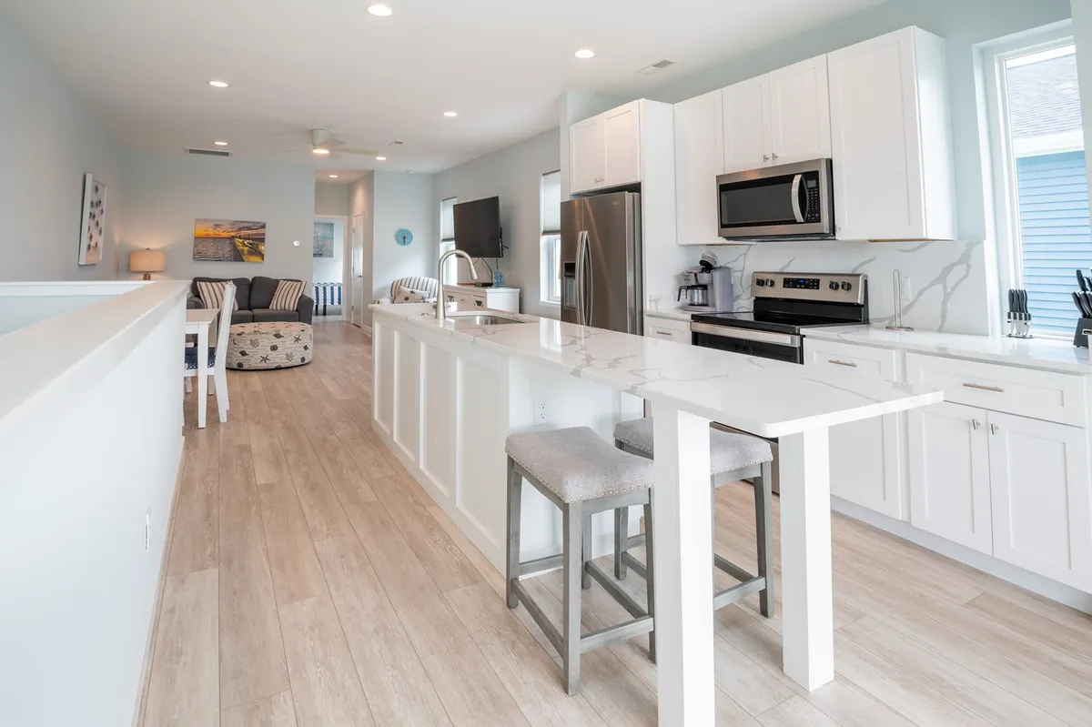 A welcoming kitchen with a large island at its center, surrounded by stainless steel appliances and an open layout. The bright, airy design invites group cooking and family gatherings, with ample counter space for food prep and casual conversations.