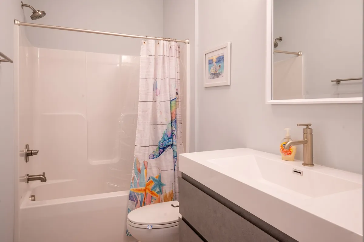A fresh and cheerful bathroom scene featuring a colorful shower curtain, modern sink, and a mirror that brightens up the space. The mood is inviting and clean, ideal for a refreshing start or end to the day.