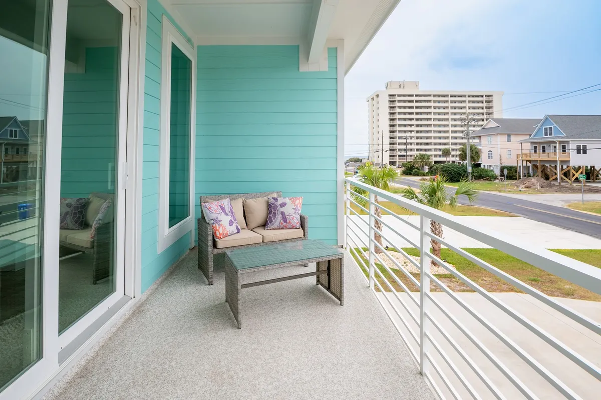This exterior scene features a comfortable outdoor seating area against a bright turquoise wall, with a clear view of the surrounding environment. The arrangement invites groups to gather, relax, and socialize while enjoying the outdoors—ideal for morning coffee or evening cocktails after a day of adventure.