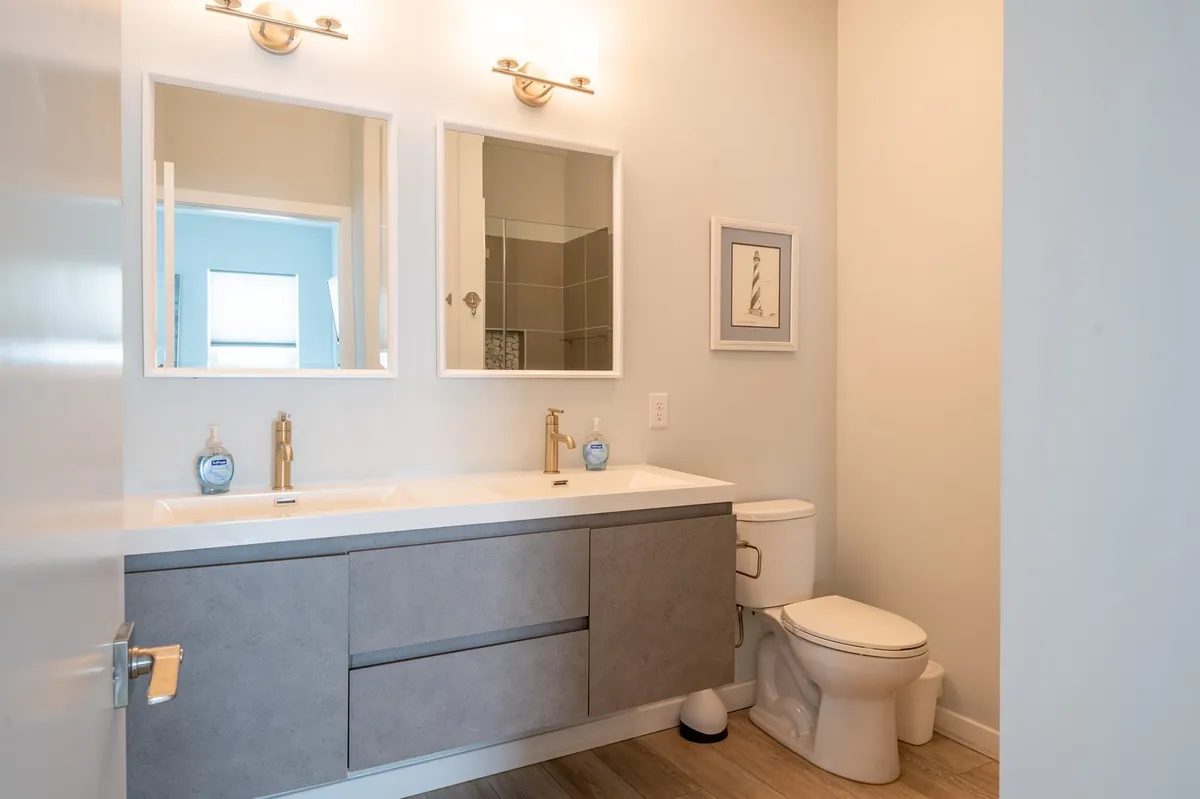 A spacious, modern bathroom with dual sinks, large mirrors, and sleek fixtures set in a neutral color palette. The room exudes calm and offers ample space for guests to get ready or unwind with self-care routines.