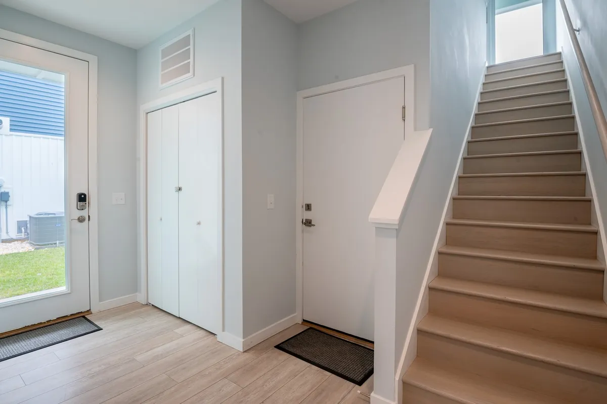A welcoming entryway featuring a front door, staircase, and closet doors, bathed in natural light. The area sets the tone for the home, inviting guests as they enter and providing a sense of arrival and privacy for each unit.