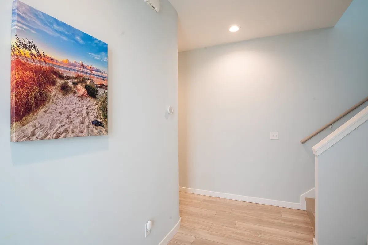 A light-filled entry area with a staircase and beach landscape artwork. The space captures first impressions as guests come and go, while the art reflects the coastal setting and the anticipation of exploring Carolina Beach’s offerings.