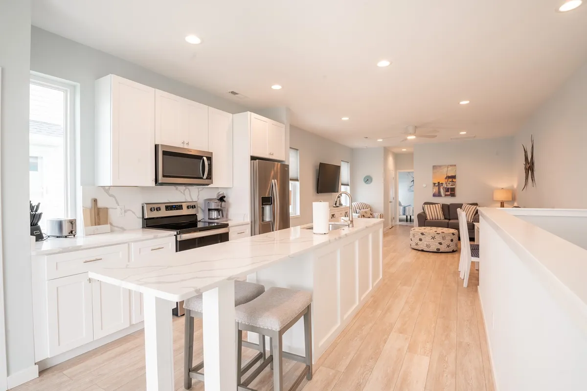 An inviting kitchen area featuring a prominent kitchen island, stainless steel appliances, and adjacent living area seating. The open-concept design supports both cooking and socializing, making this space ideal for shared meals and group activities.