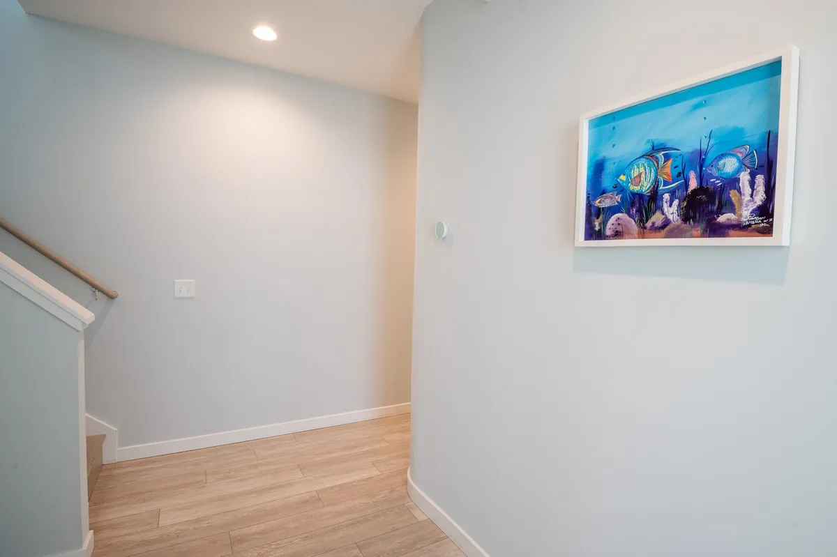 A welcoming staircase with colorful artwork lining the wall. The space feels open and inviting, suggesting the first steps into Tide and Seek after a day out exploring. The staircase connects the indoors to other parts of the home, symbolizing the transition from the world outside to the comfort inside.