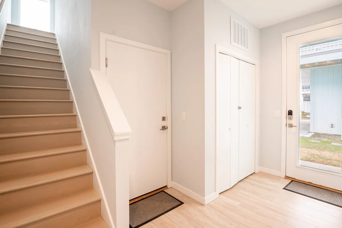 A broader view of the entrance with the front door, stairway, and closet doors, creating a sense of coming home after a busy day or preparing to head out for new experiences. The open layout suggests ease of movement and readiness for seasonal adventures.